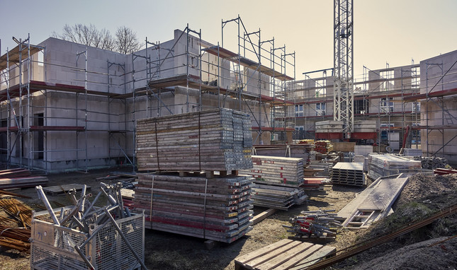 Baustelle mehrerer Gebäude mit Kran und Baumaterial