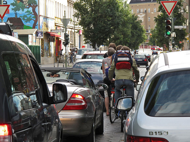 Fahrradfahrer quetschen sich an Autos eng vorbei