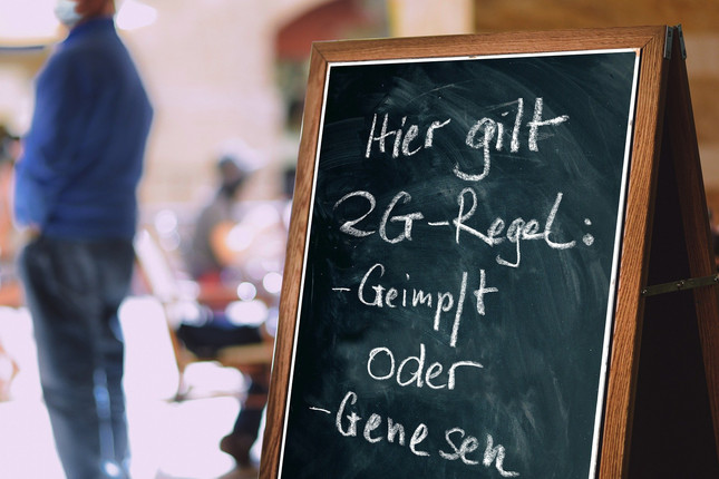 Tafel mit Aufschrift "Hier gilt 2G-Regel: geimpft oder genesen"