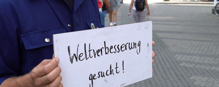 Ein Mann mit einem Schild: Weltverbesserung gesucht  - Link auf: Das Prinzip