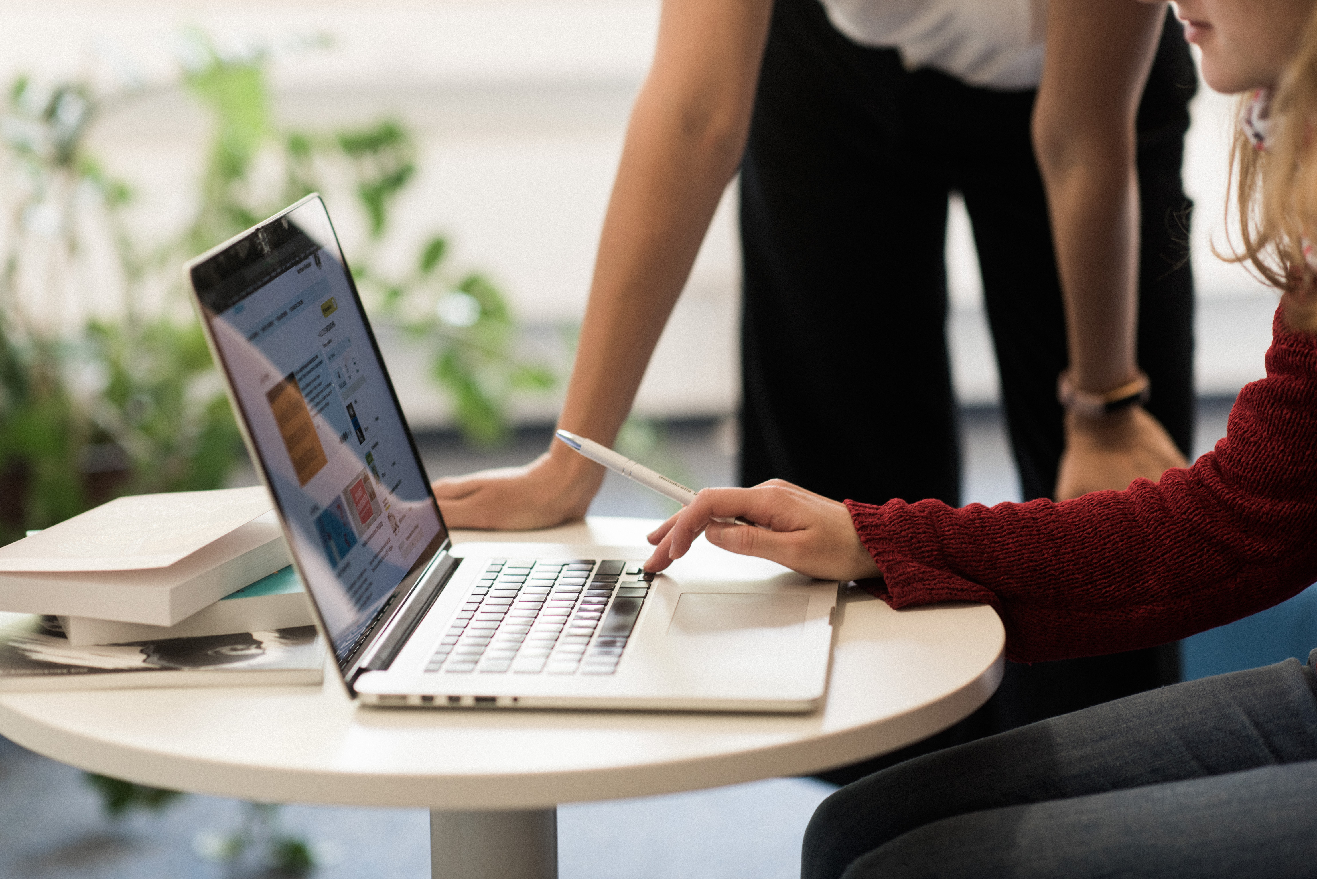 Kleiner Tisch mit Laptop, darüber zwei Menschen